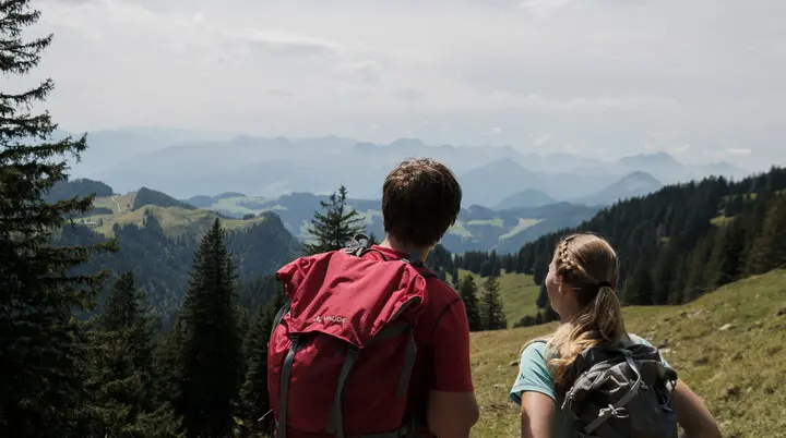 Ein Mann und eine Frau beim Wandern Wanderer in den Chiemgauer Alpen - sie genießen den Ausblick über mehrere Gipfel. | © DAV/Hans Herbig