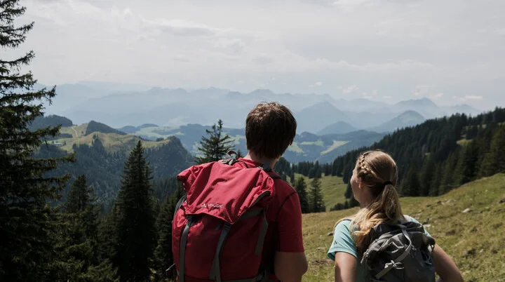 Ein Mann und eine Frau beim Wandern Wanderer in den Chiemgauer Alpen - sie genießen den Ausblick über mehrere Gipfel. | © DAV/Hans Herbig